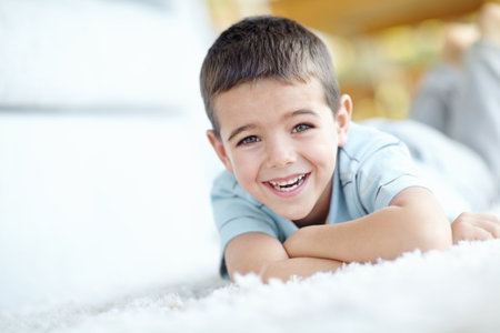 Home, relax and portrait of child on carpet for weekend enjoyment, break and satisfaction. Happy, boy and face of kid by mat on floor of house for development, wellness and peace with fun in morningの写真素材