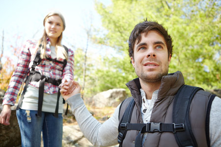 Support, forest or couple holding hands in nature for romantic travel, outdoor adventure or journey. Love, help or people in woods together on holiday vacation, mountain trip or break to explore parkの写真素材
