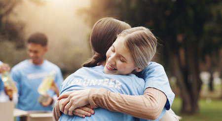 Women, volunteer and friends hug in park together for solidarity, support or sustainability at green ngo. Gratitude, nature and people in embrace for teamwork, community care or social responsibilityの写真素材