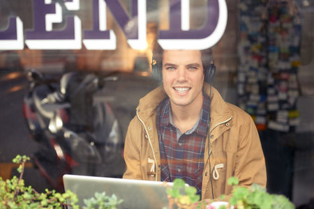 Man, portrait and laptop with headphones in coffee shop for remote work, music or smile in morning....