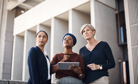 Balcony, business people or research on tablet in office for planning, review or company feedback. Teamwork, city or smart women thinking in agency for networking online, social media update and newsの写真素材