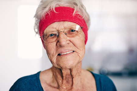 Old woman, portrait and home for sportswear fitness, headband and exercise for flexibility. Female person, senior wellness and workout for physical activity, retirement and glasses for trainingの写真素材