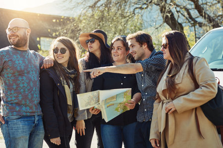 Friends, paper map and pointing for travel, journey and finding direction on road trip. Men, women...