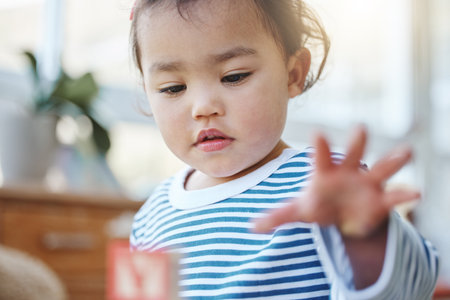 Playing, toddler and toys in house, cute and growth with development of child, curious and building blocks. Childhood, baby and fun for girl in home, youth and adorable on weekend, hand and learningの写真素材