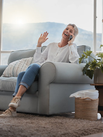 Mature woman, phone call and happy on sofa with memory, contact or listen in living room at house. Person, smartphone and smile with conversation, laughing or network with connection in apartmentの写真素材