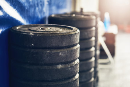 Weight, gym and metal gear on floor for strength training, exercise and bodybuilding equipment. Health, wellness and sport club with iron stock for workout and weightlifting practice with steelの写真素材