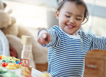 Games, toddler and toys in house, smile and growth with development of child, curious and building blocks. Childhood, baby and fun for kid in home, youth and adorable in weekend, hand and learningの写真素材