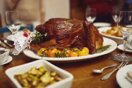 Table, turkey and feast for festive, thanksgiving and meat with vegetables, dinner and celebration. Chicken, protein and glass for drink, holiday and buffet in dining room, Christmas and food in homeの写真素材
