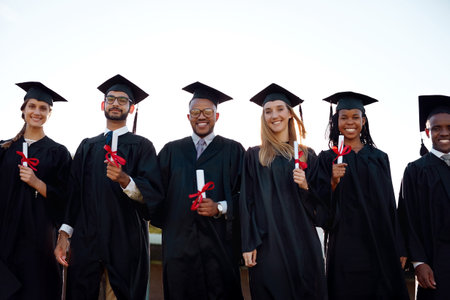Graduation, outdoor or portrait of students with class at university for education, learning or success. College, diploma or happy people at campus with degree, smile or certificate for empowermentの写真素材