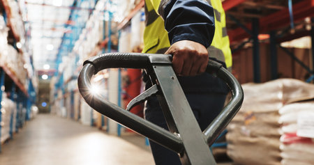 Warehouse, hand and worker pull pallet truck for supply chain, restock or moving freight. Factory, person and trolley for cargo storage, distribution logistics and back in shipping industry closeupの写真素材