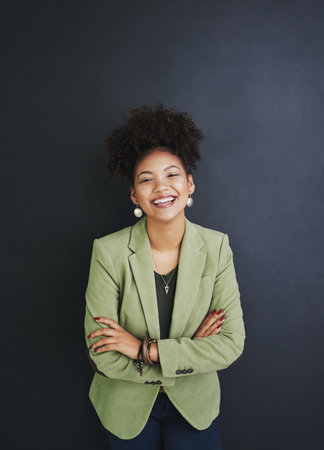 Portrait, arms crossed and happy business woman in studio for pride or job experience. Face, confidence and African professional, expert or creative journalist laughing isolated on black backgroundの写真素材