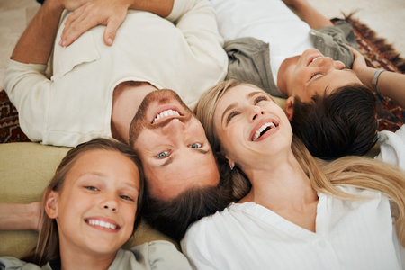 Love, portrait and smile with family in living room of home together for love or bonding from above. Face, happy or security with mother, father and sibling children in apartment to relax for breakの写真素材