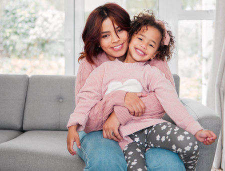 Happy mother, portrait and hug with child for love, care or support in embrace on sofa at home. Mom, little girl or daughter with smile for bonding, childhood or youth on mothersday on couch at houseの写真素材