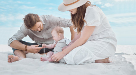 Parents, baby and play with sand at beach, relax and together on ground for love, care and vacation. Mother, father and infant boy for connection, learning or outdoor with holiday by seaside in Italyの写真素材