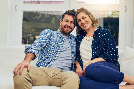 Happy couple, portrait and relax with sofa for bonding, weekend or fun holiday together at home. Young man, woman or lovers with smile on couch for relationship, marriage or commitment at houseの写真素材