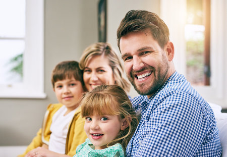 Family, portrait and happy in house for relax, bonding and support with parents, love and care. Mom, dad and children in living room for comfort, relationship and embrace together on weekend on sofaの写真素材