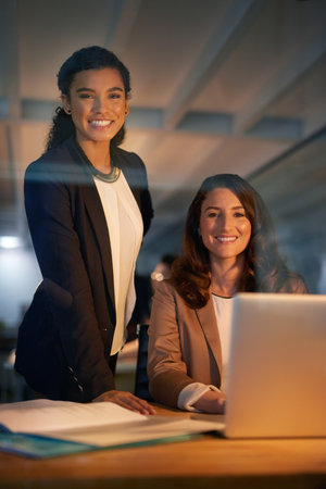Research, portrait and women in night, laptop and overtime for project of web designer and smile. Startup, collaboration and employees in creativity, happy and together in business and plan in officeの写真素材