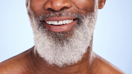 Smile, mouth and black man for oral hygiene and closeup, teeth and beard on blue background. Dentist, mature and face for male person in studio, dental care and cosmetic for healthy and fresh breathの写真素材