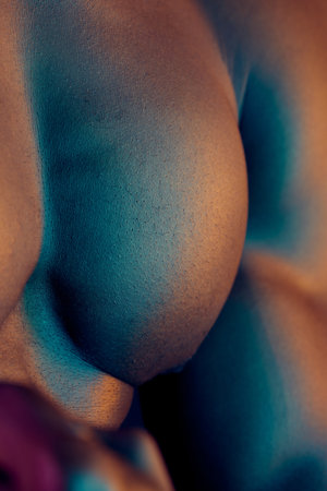 Man, closeup and muscle in studio, shirtless and skin for chest or strong pectoral for fitness. Male person, body and bodybuilder for health, flexing and athlete for topless wellness in darkの写真素材