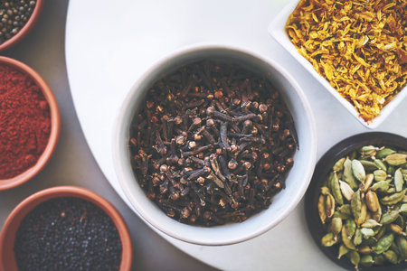 Above, bowl and clove in gray background for spices, powder and variety for sensory appeal with culinary. Studio, condiment and flavor for cooking with ingredients, texture and seasoning collectionの写真素材