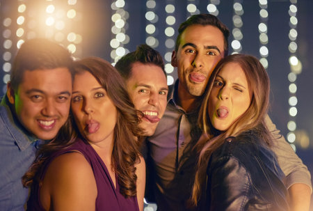 Friends, people and happy in nightclub on portrait with light, fun and night out for break, party and enjoy. Disco, entertainment and happy at pub for nightlife on date, bonding and love or supportの写真素材