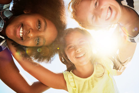 Friends, low angle and portrait of children on camp for friendship, playing and fun together. Diversity, youth and girls huddle in circle for childhood, game and hug for school, recess and playgroundの写真素材