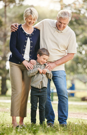 Smile, nature and grandparents with child at outdoor park for connection on family holiday together. Happy, hug and boy with grandmother and grandfather in field for bonding on vacation in Californiaの写真素材