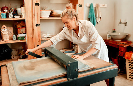 Production, woman and clay press in workshop for pottery, creativity and project for development. Artist, design and process for art deco with tool in small business for product and career in studioの写真素材