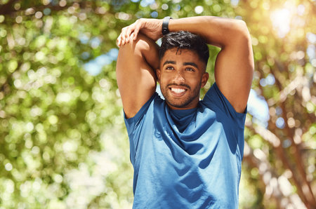 Fitness, happy man and stretching arm at park for wellness, healthy body and start exercise. Flexible, runner or warm up muscle outdoor to prepare for workout, training or thinking of sports marathonの写真素材