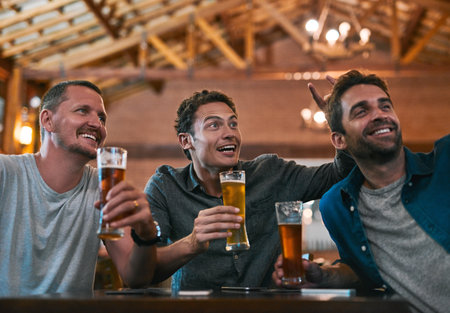 Friends, beer and watching tv in pub with drinks as celebration for sports, happiness and bonding. Alcohol, men and streaming game in restaurant for birthday party, event and reunion in Germanyの写真素材