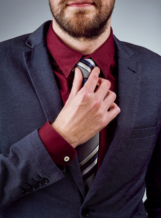 Professional, businessman and hands on tie in studio as lawyer at firm with goal for company growth or future. Male person, formal and corporate for mission or project in agency on grey backgroundの写真素材