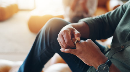 Wedding ring, anxiety and hands of man on sofa for guilt of divorce, cheating or infidelity. Nervous, jewelry and closeup of male person with marriage breakup, separation or problem at counselling.の写真素材