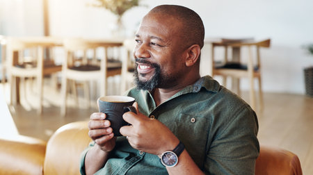 Coffee, thinking and black man in home with memory, ideas or reflection of past with happiness. Cappuccino, smile and African male person drinking caffeine latte on sofa for relaxing at house.の写真素材