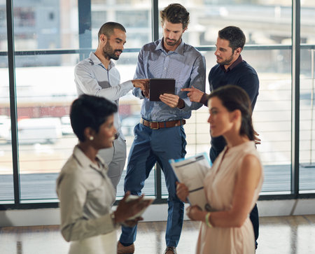 Business people, tablet and feedback for planning, collaboration and networking in office with diversity. Partnership, technology and research for project management, development and cloud computingの写真素材
