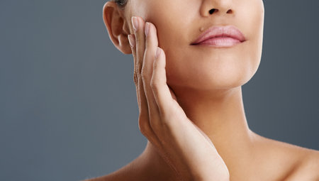 Skincare, lips and dermatology with woman in studio for cosmetic treatment, aesthetic and facial. Spa, glow and shine with person on gray background for cosmetology, self care and mockup spaceの写真素材