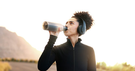 Woman, drinking water or music in nature for fitness, hydration or electrolytes for energy. Girl,...