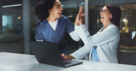 Night, doctor and nurse on laptop high five for good news, goals or teamwork achievement in...