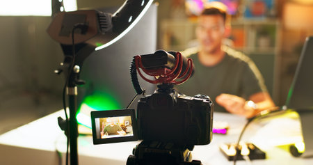 Man, influencer and video recording with camera for online streaming, content creation or social media at home. Male person, vlogger or young streamer with equipment or ring light for live broadcastの写真素材