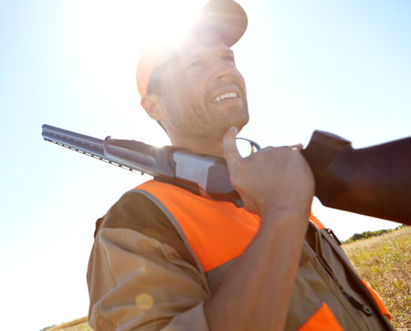 Man, thinking and outdoor nature for hunting, rifle and stalking prey adventure in bush. Mature person, practice and hunter planning in field for shooting games, sun flare and tracking gear in sportsの写真素材