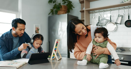Parents, children and homework with baby in kitchen for bonding, care and love with support in family house. Father, mother and daughter with infant, happy and tablet for online course at apartmentの写真素材