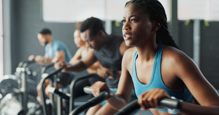 People, fitness and stationary bike at gym for exercise, training and workout with sweat. Cycling...