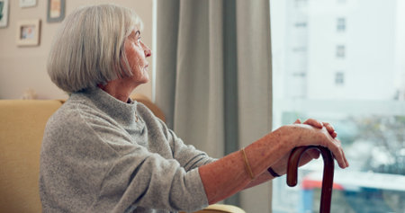 Senior woman, cane and sofa for thinking in home for memory, mobility or rehabilitation by window....