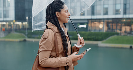 Woman, outdoor and smile with umbrella on smartphone with rain drops or commute for job interview. Female employee, profile and smile on internet with map for direction or navigation for directionの写真素材