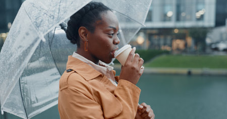 Outside, black woman and smile with umbrella or coffee in rainy weather for commuting or travel to work. Female employee or professional, profile and thinking tea in city with water drops on journeyの写真素材