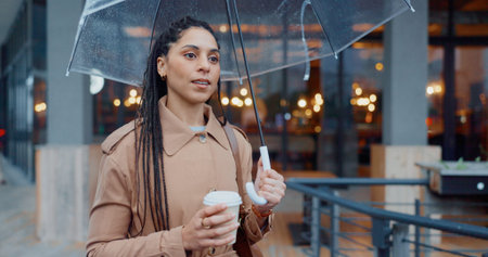 Outside, woman and thinking with umbrella or tea in rainy weather for commuting or travel to work....