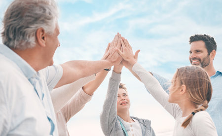 High five, motivation and support with family on beach together for holiday, travel or vacation in summer. Smile, sky or success with senior people, parents and kids on coast for tropical getawayの写真素材