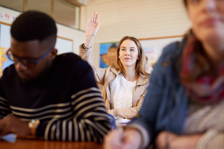 Woman, student and hand raised for education, classroom or happy with solution for test at university. Person, thinking and excited for learning, question or answer for quiz with diversity at collegeの写真素材