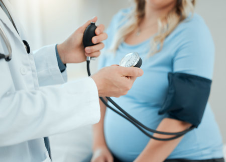 Hospital, pregnant woman and doctor with checkup for blood pressure, monitor heart rate and appointment. Healthcare, patient and obstetrician with consultation for pregnancy, hypertension or wellnessの写真素材