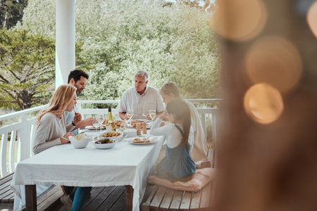 Lunch, meal and reunion with big family on home porch for celebration or festive holiday. Cooking, roast or food with people eating in house together for party event or social gathering vacationの写真素材