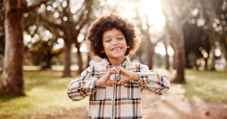 Portrait, outdoor and boy with heart hands, nature and support with smile, happiness and review. Face, childhood and kid in park, gesture and emoji with symbol for love, icon and kindness with trustの写真素材